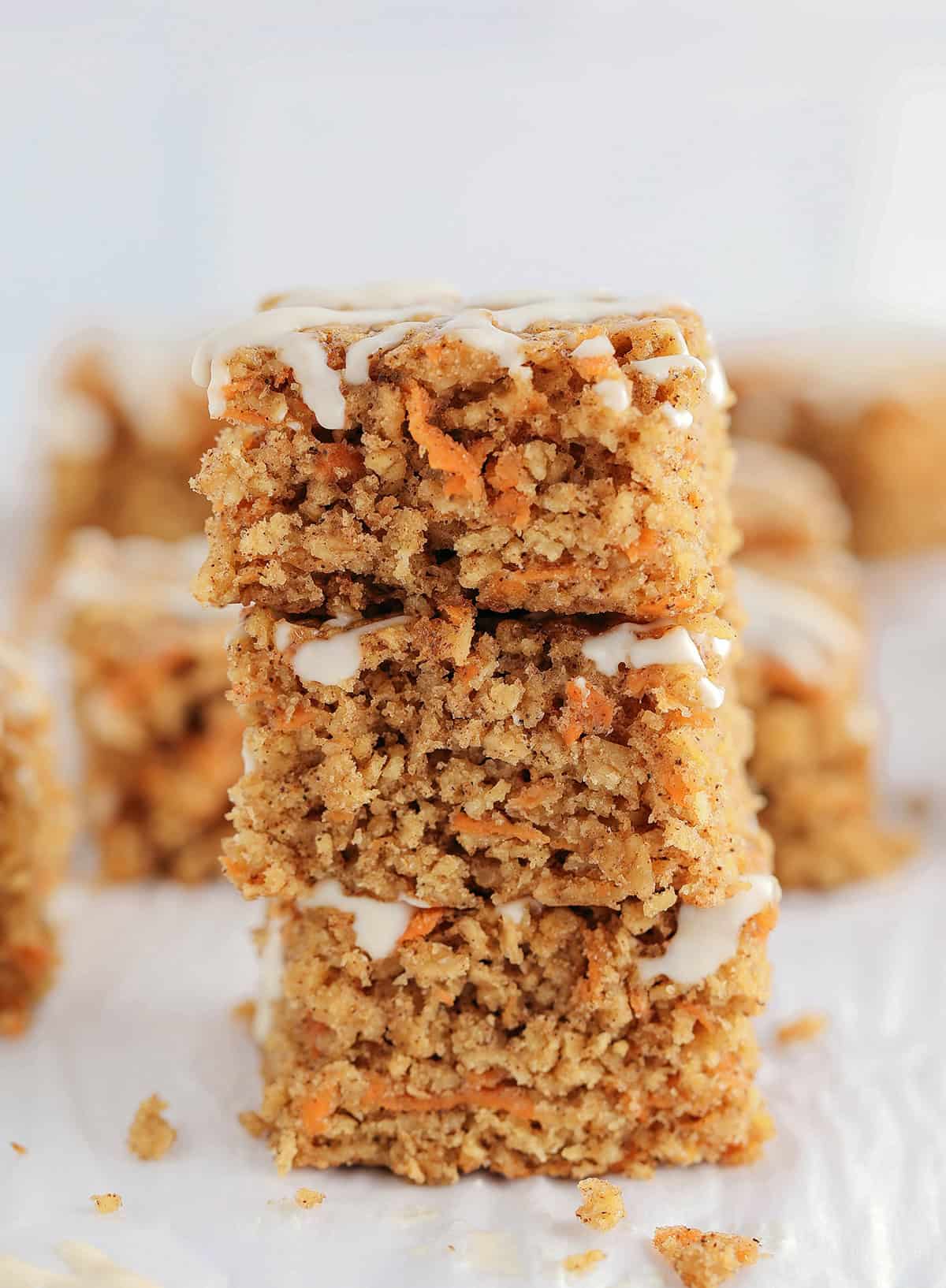 These EASY Healthy Carrot Cake Oatmeal Breakfast Bars make a quick on-the-go breakfast, snack or wholesome dessert! Made with zero refined sugar and drizzled with a delicious maple cream cheese frosting.