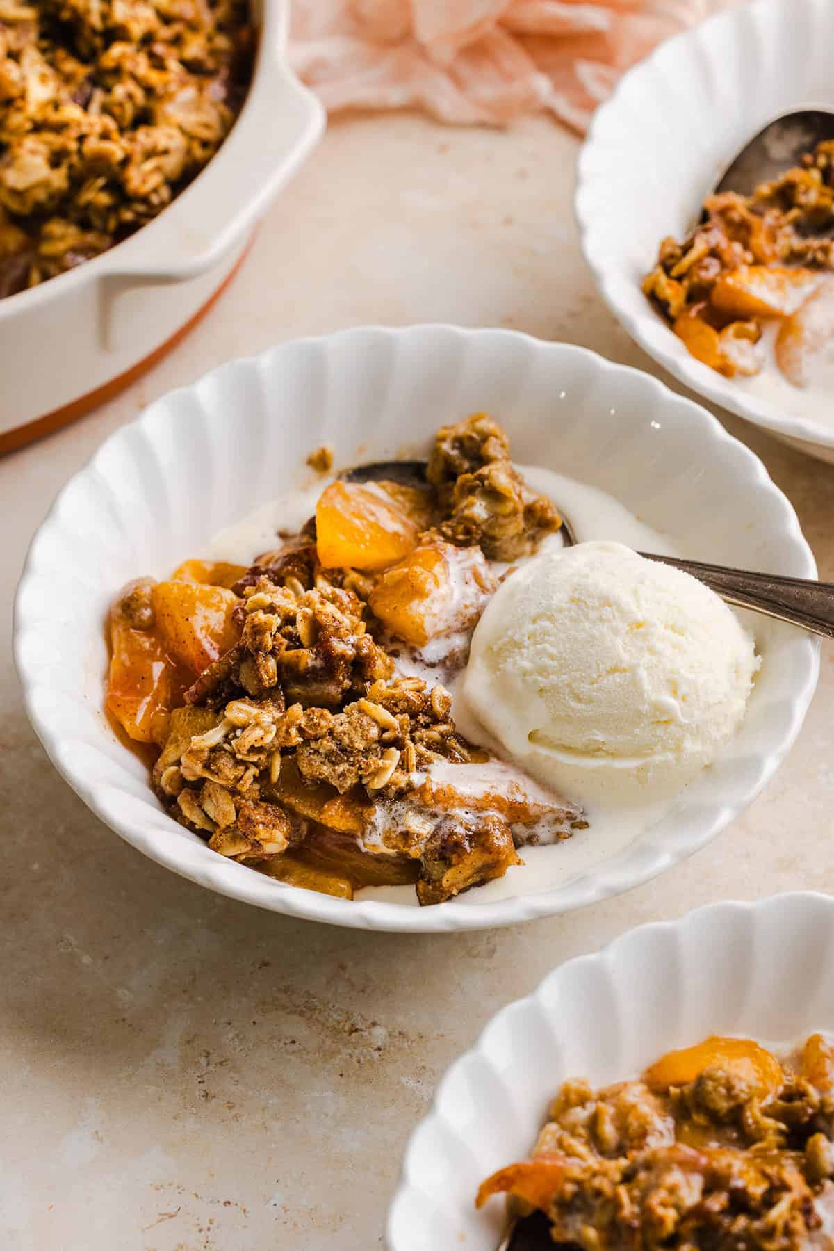 This Healthy Peach Crisp recipe is made with juicy fresh peaches and a wholesome oat pecan crumble naturally sweetened with maple syrup. An easy summer dessert that is warm, cozy, and perfect with vanilla ice cream!