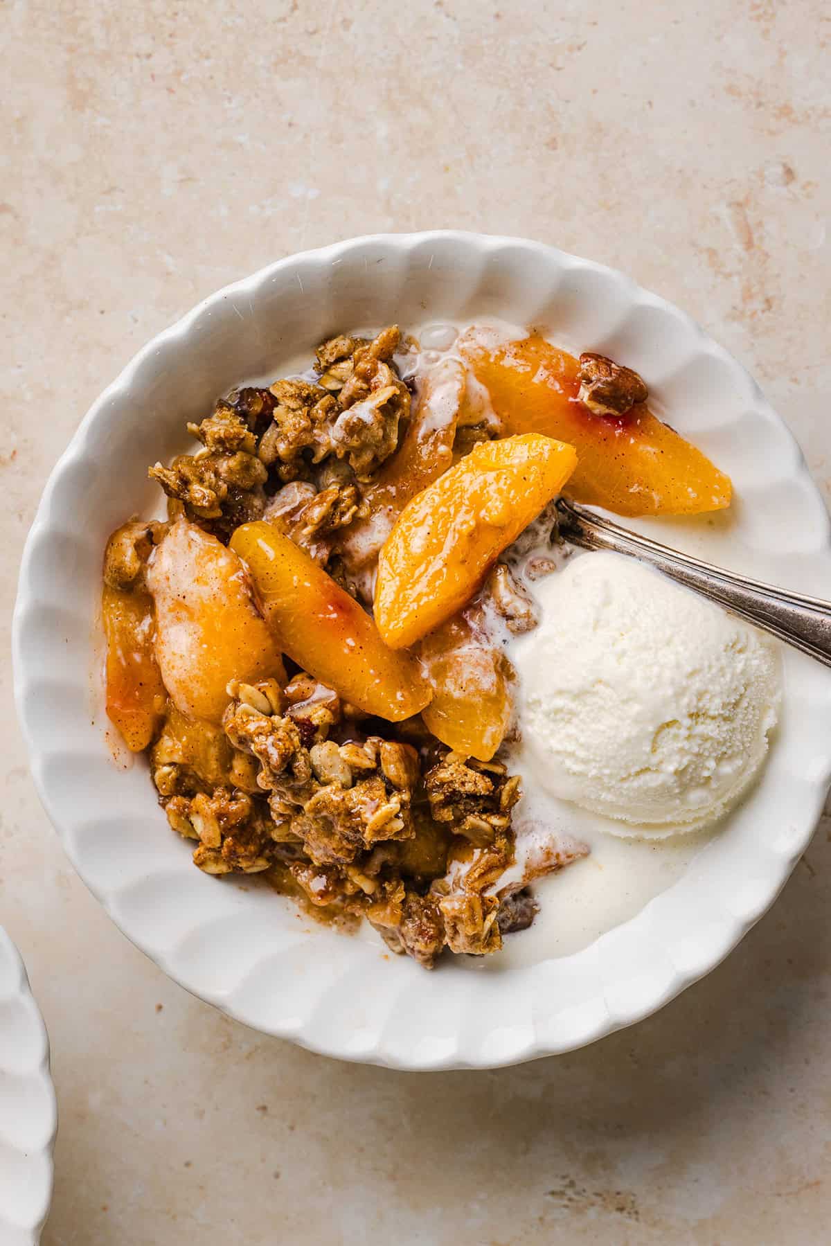 This Healthy Peach Crisp recipe is made with juicy fresh peaches and a wholesome oat pecan crumble naturally sweetened with maple syrup. An easy summer dessert that is warm, cozy, and perfect with vanilla ice cream!