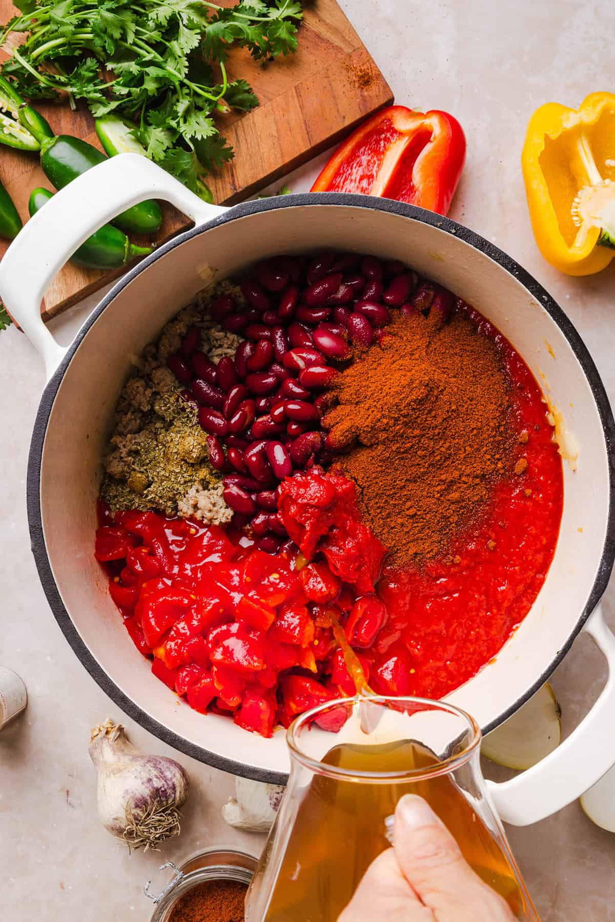 Adding beef broth to healthy turkey chili along with tomatoes, kidney beans and spices.